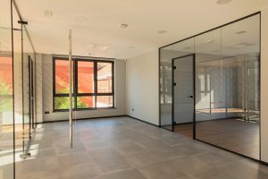 New and empty office interior, entrance wall of glass, during day.